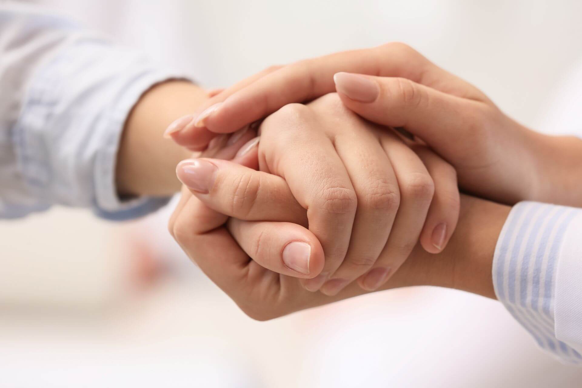 Mani di un adulto che stringono con cura la mano di un bambino, simbolo di sostegno, protezione e vicinanza emotiva.